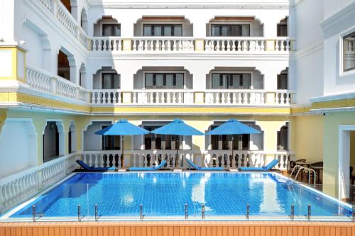 會安的住宿－Le Pavillon Hoi An Gallery Hotel & Spa，一座带蓝色遮阳伞的建筑前的游泳池