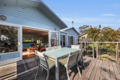 a blue house with a table and chairs on a deck at Blue on Collins in Merimbula