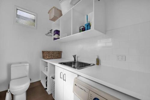 a white bathroom with a sink and a toilet at Blue on Collins in Merimbula