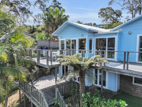 a blue house with a porch and a deck at Blue on Collins in Merimbula