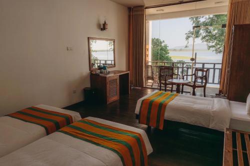 a hotel room with two beds and a balcony at Yala Oga Reach Hotel in Tissamaharama