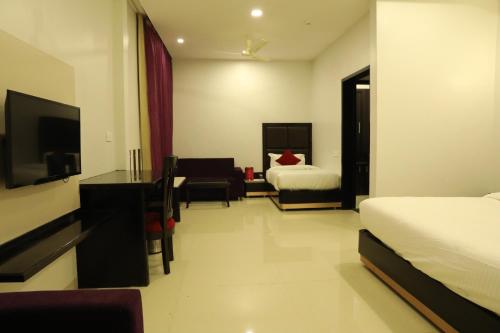 a hotel room with a bedroom with two beds and a desk at Chandra Grand in Jodhpur