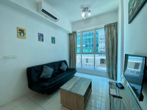 a living room with a black couch and a television at SA Sutera Avenue Homestay Opposite Imago KK in Kota Kinabalu