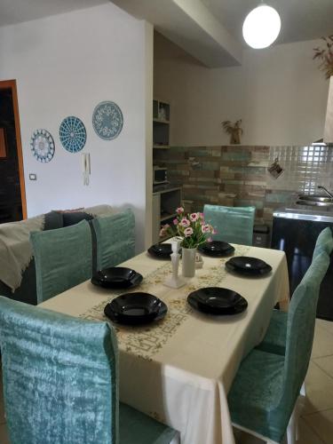 tavolo da pranzo con panno bianco e sedie verdi di Panoramic apartment a Shkodër