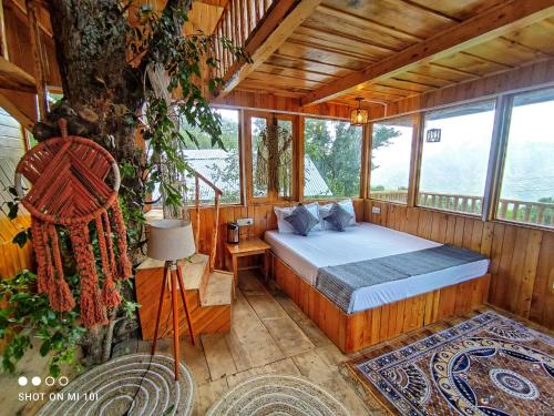 a bedroom with a bed in a room with a tree at The Tree Top Treehouse Jibhi in Jibhi