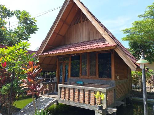 a small house with a porch in a garden at Palanta Roemah Kajoe Syariah Villa in Kampungdurian