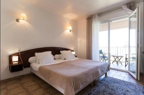 a bedroom with a large bed and a balcony at Hotel-Restaurant Le Vieux Moulin in Centuri