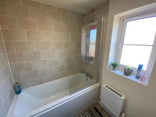 a bathroom with a bath tub and a window at Single bedroom - Hampton Water, Peterborough in Peterborough