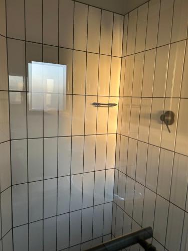 een badkamer met een witte tegelmuur en een douche bij Fusion Guest House in Kempton Park