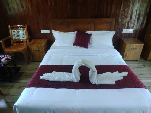 uma cama grande com duas toalhas brancas em Don's River Valley Jungle Resort em Maraiyūr