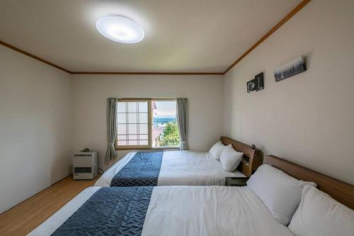 two beds in a room with a window at SHIONE in Otaru