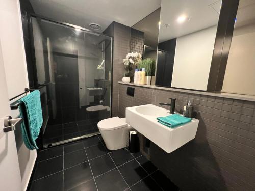 y baño con lavabo, ducha y aseo. en Midnight Luxe 1BR Executive Apartment in the heart of Braddon Views L7 Pool Sauna Gym Secure Parking Wifi Wine, en Canberra