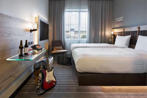a hotel room with a bed and a guitar in it at Moxy Katowice Airport in Pyrzowice