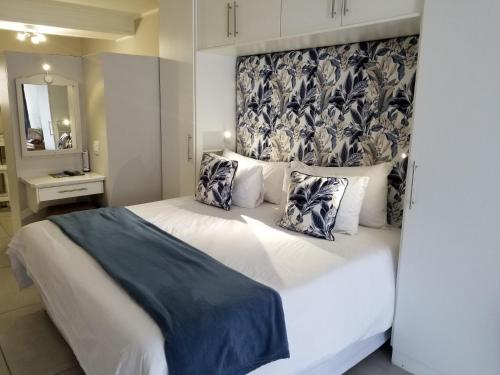 a bedroom with a large white bed and a mirror at Riviera Hotel Hartenbos in Mossel Bay