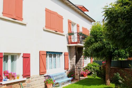a building with red shutters and a bench in a yard at La Maison des Chats in Saint-Mary-le-Plain