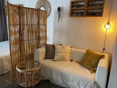 - un canapé blanc avec des oreillers dans l'établissement Studio cosy rez de jardin à 10 mn des plages, à Baie-Mahault