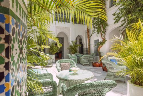 a patio with tables and chairs and plants at Riad Idra in Marrakech