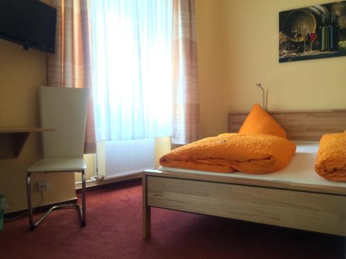 een slaapkamer met een bed met oranje kussens en een raam bij Hotel Arns in Bernkastel-Kues