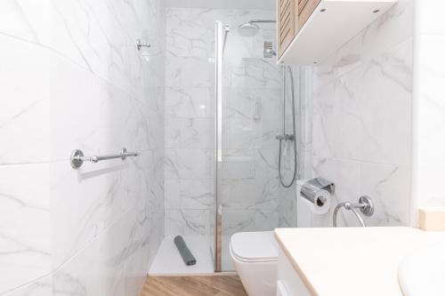 uma casa de banho branca com um chuveiro e um WC. em Oceanfront 2 bedrooms Holiday Home in Tenerife South em San Miguel de Abona