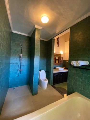 a bathroom with a tub and a toilet and a sink at Puri Ayu in Canggu