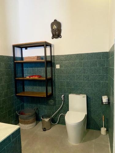 a bathroom with a toilet and a green tiled wall at Puri Ayu in Canggu