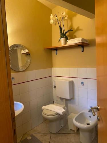 een badkamer met een toilet, een wastafel en een spiegel bij Civico 8 in Rivarolo Canavese