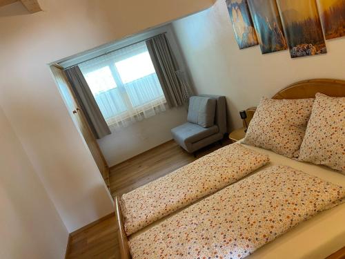 a bedroom with a bed and a chair and a window at Sunside Apartment in Zell am Ziller