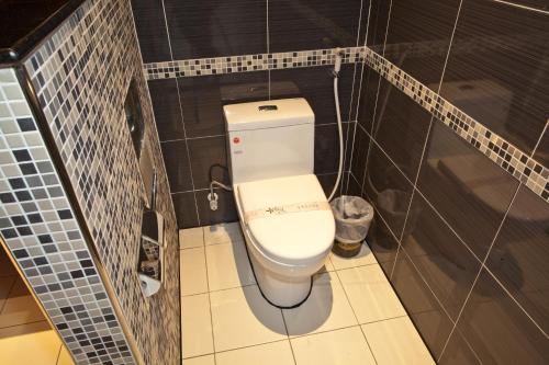 a bathroom with a toilet in a tiled room at Wei Feng Hotel - Kaohsiung in Nanzi