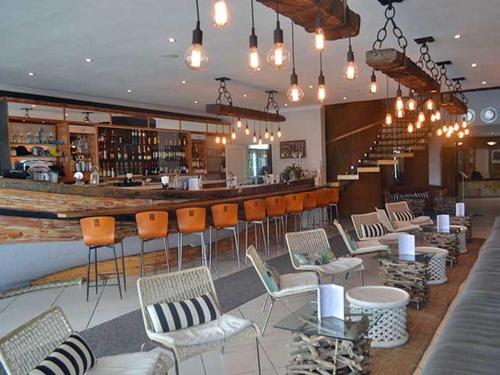 a restaurant with a bar with chairs and a counter at Riviera Hotel Hartenbos in Mossel Bay