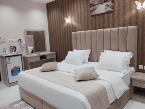 a bedroom with a large bed with white sheets and pillows at العلي للشقق المخدومة Alalihotel in Hafr Al-Batin