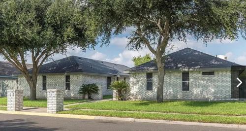 a white brick house with trees in front of it at PEBBLES' BEACH HOUSE in Edinburg