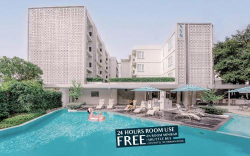 a swimming pool in front of a hotel with two tall buildings at SYN Boutique Hotel in Chiang Mai