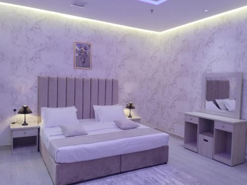 a white bedroom with a bed and a mirror at العلي للشقق المخدومة Alalihotel in Hafr Al Baten