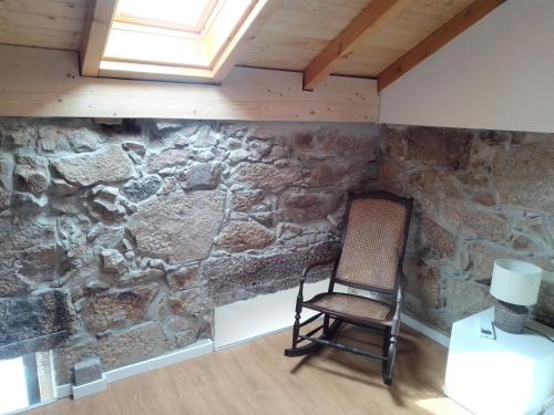 une chaise dans une pièce avec un mur en pierre dans l'établissement Casa da Florbela, à Fafe