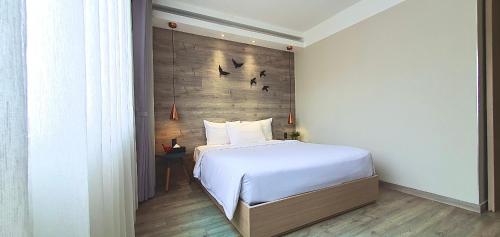a bedroom with a white bed and a wooden wall at The Luxe Da Lat in Da Lat