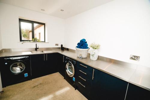 a kitchen with a sink and a washing machine at Sandy Barn *BRAND NEW* Barn Conversion in Tunstead