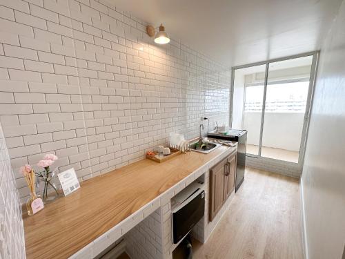 a kitchen with white brick walls and a wooden counter top at Happiness sleep C3 in Ban Bang Phang