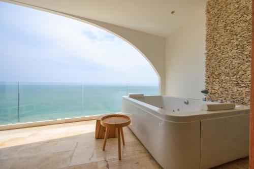Luxury Penthouse - Khanom في Ban Plau: حمام مع نافذة كبيرة وحوض استحمام ومقعد