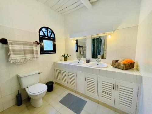 a bathroom with a toilet and two sinks and a mirror at Casa Hera Diani in Diani Beach