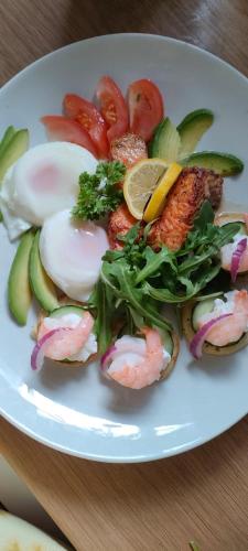 Un plato de comida con camarones y verduras en una mesa. en Cuisinease, en Ollerton