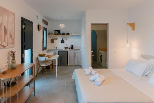 Cet appartement comprend une chambre avec un lit blanc et une cuisine. dans l'établissement 64steps Studio, à Anáfi