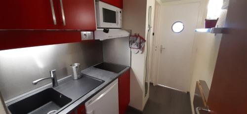 uma pequena cozinha com um lavatório e um micro-ondas em La Mongie, Studio pieds des pistes, parking intérieur privé em La Mongie