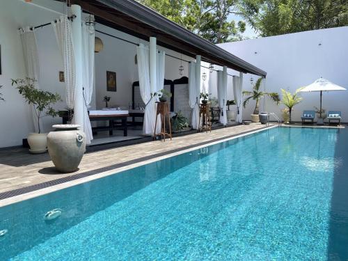 - une piscine en face d'une villa avec une table dans l'établissement D' Art VILLA RETREAT AND SPA, à Tangalle