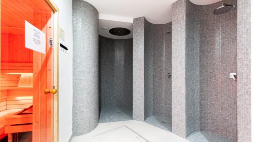 La salle de bains est pourvue d'une douche et de murs carrelés gris. dans l'établissement Stone Hill Apartament Wellness z basenem jakuzi saunami prywatnym garażem i rowerami w cenie, à Szklarska Poręba