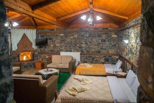a room with two beds and a living room with a fireplace at Ta Skalopatia in Palaios Agios Athanasios