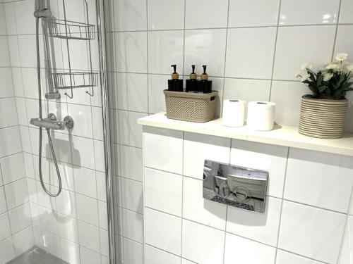 a white tiled bathroom with a shower with wine bottles on a shelf at Scandpoint Apartment Lillestrom -Cosy 3 rooms flat with free Parking, EV Charger 18 min from Airport in Lillestrøm