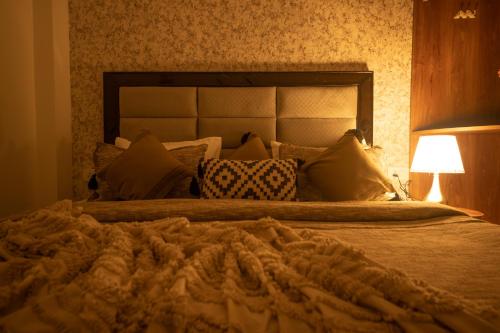 a bedroom with a large bed with pillows and a lamp at Perfectstayz Value Homes Mussoorie 120 meters uphill in Mussoorie