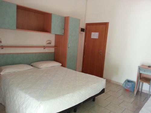a small bedroom with a bed and a wooden door at Hotel La Parigina in Cesenatico
