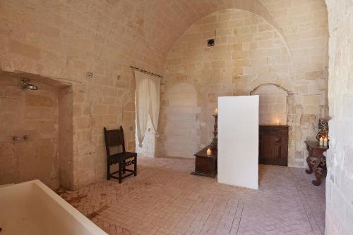 a bathroom with a tub and a chair in a room at Sextantio Le Grotte Della Civita in Matera