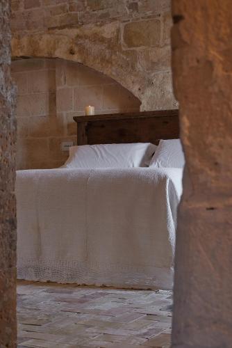 a bedroom with a bed in a stone wall at Sextantio Le Grotte Della Civita in Matera